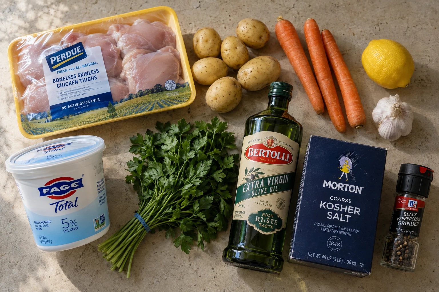 A sample countertop with chicken, potatoes, carrots, lemon and herbs